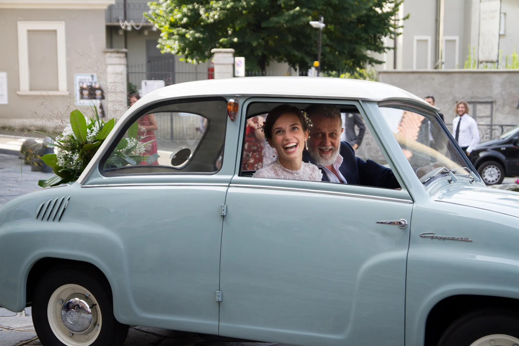 Sposi che ridono dentro un'auto d'epoca azzurra